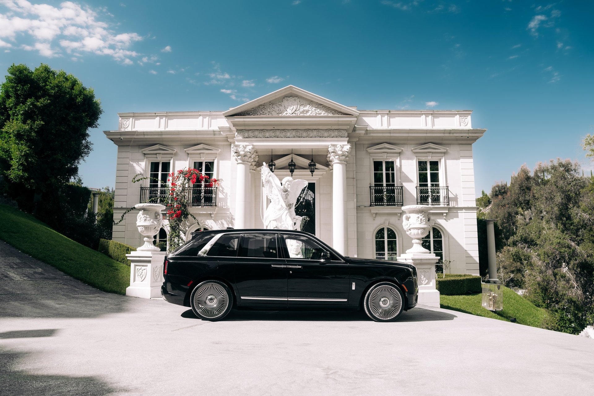 Executive stepping out of luxury Rolls Royce at elegant estate entrance